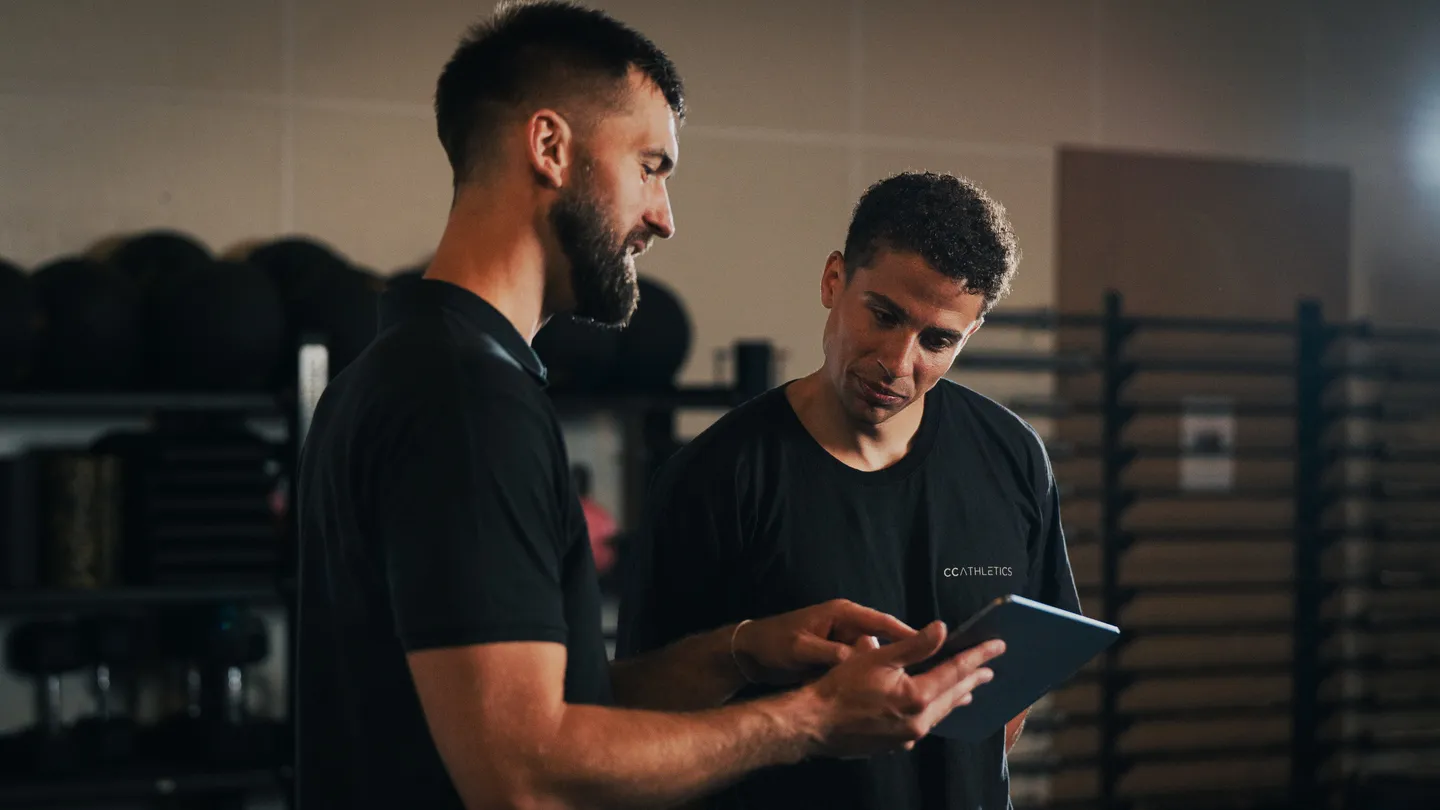 A coach and an athlete looking at test results together on a tablet